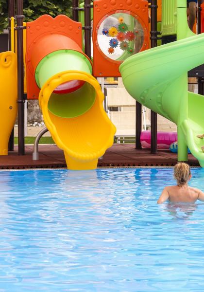 Piscina con scivolo colorato e bambini che giocano.