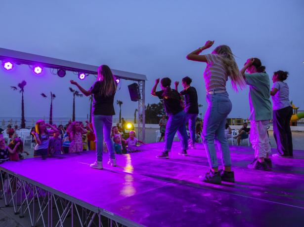 Spectacle du soir à la plage avec enfants et jeunes sur scène.