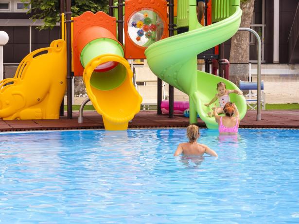 Piscina con scivolo colorato e bambini che giocano.