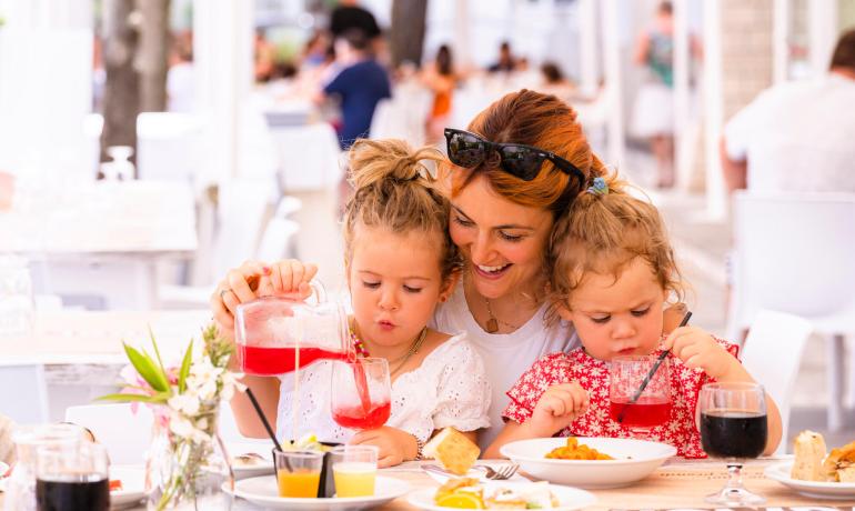 Madre e figlie a pranzo, godendosi bevande e cibo.
