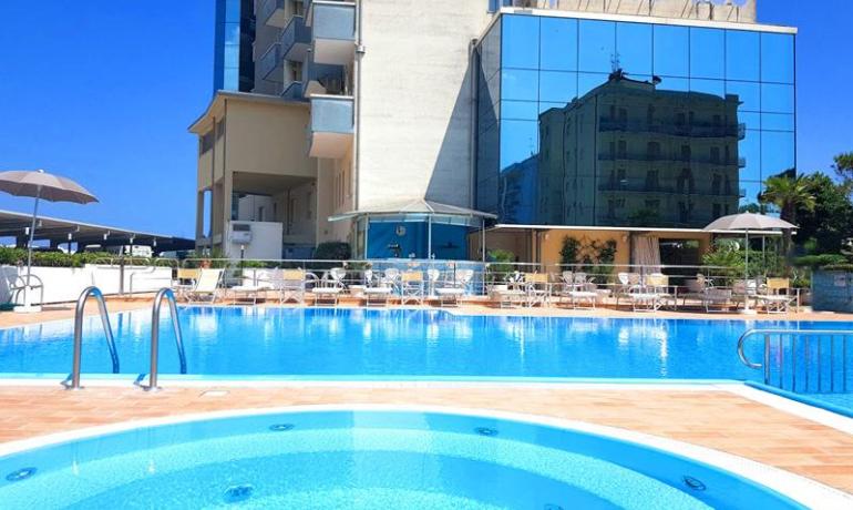 Piscina dell'hotel Palace Lido con lettini e ombrelloni.