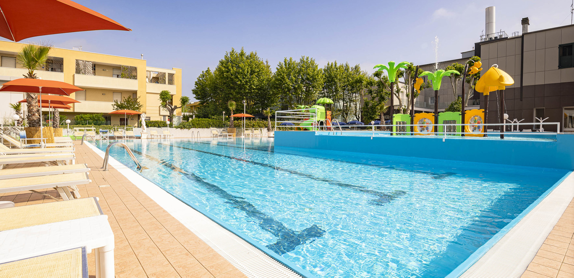 Piscina luminosa con sdraio e giochi colorati per bambini, atmosfera estiva e rilassante.