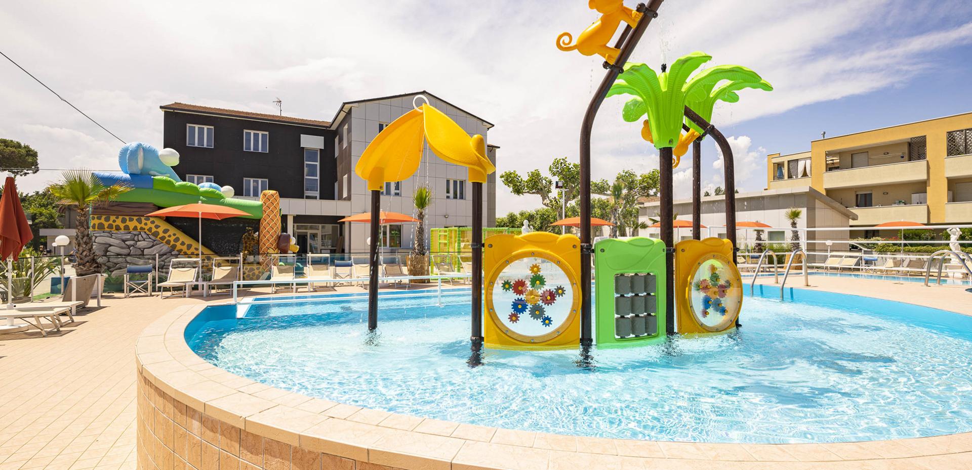 Area giochi per bambini con scivolo giallo e recinto colorato.