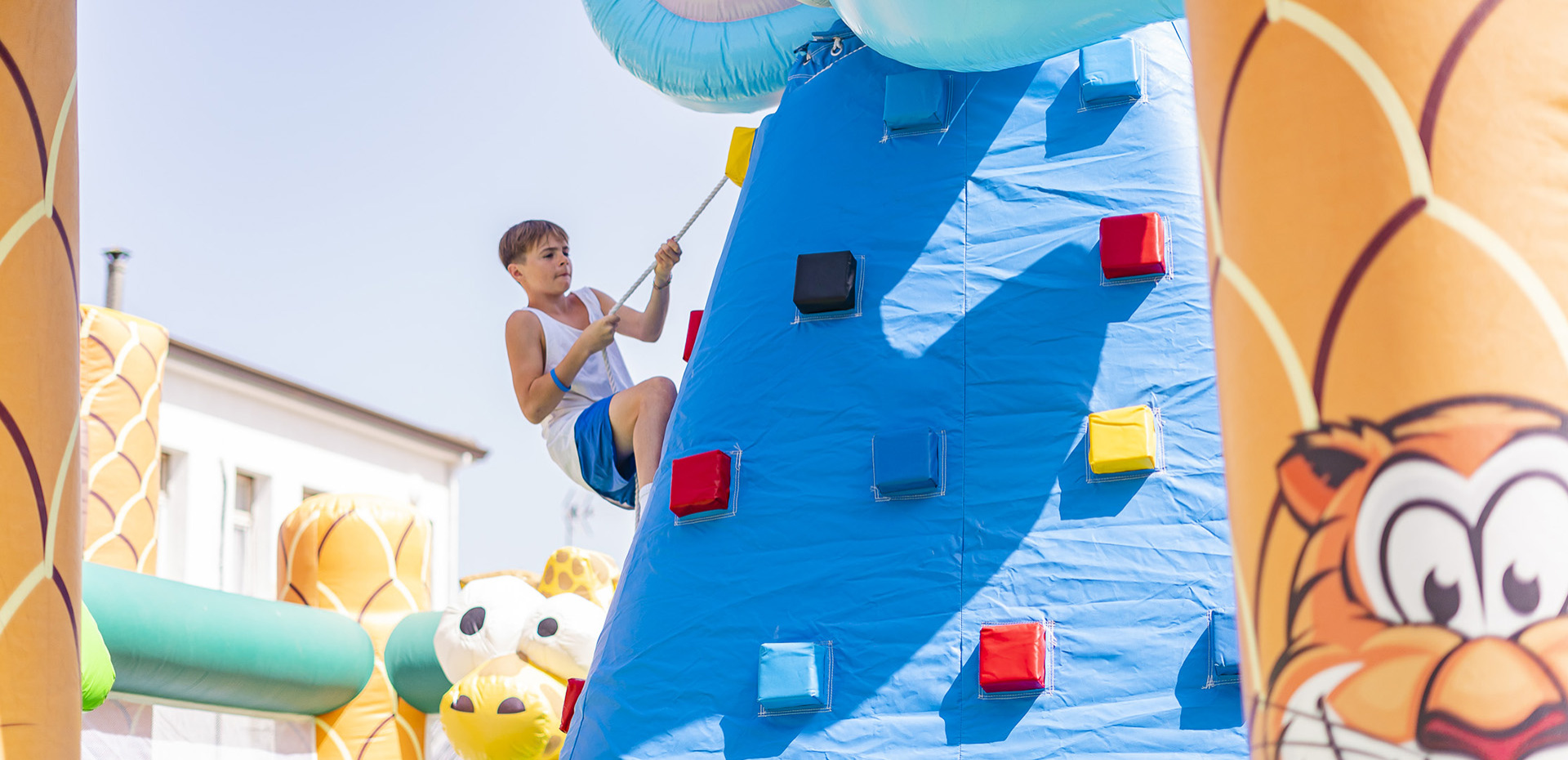 Famiglia in camera d'albergo, bambini giocano sui letti con peluche colorati.
