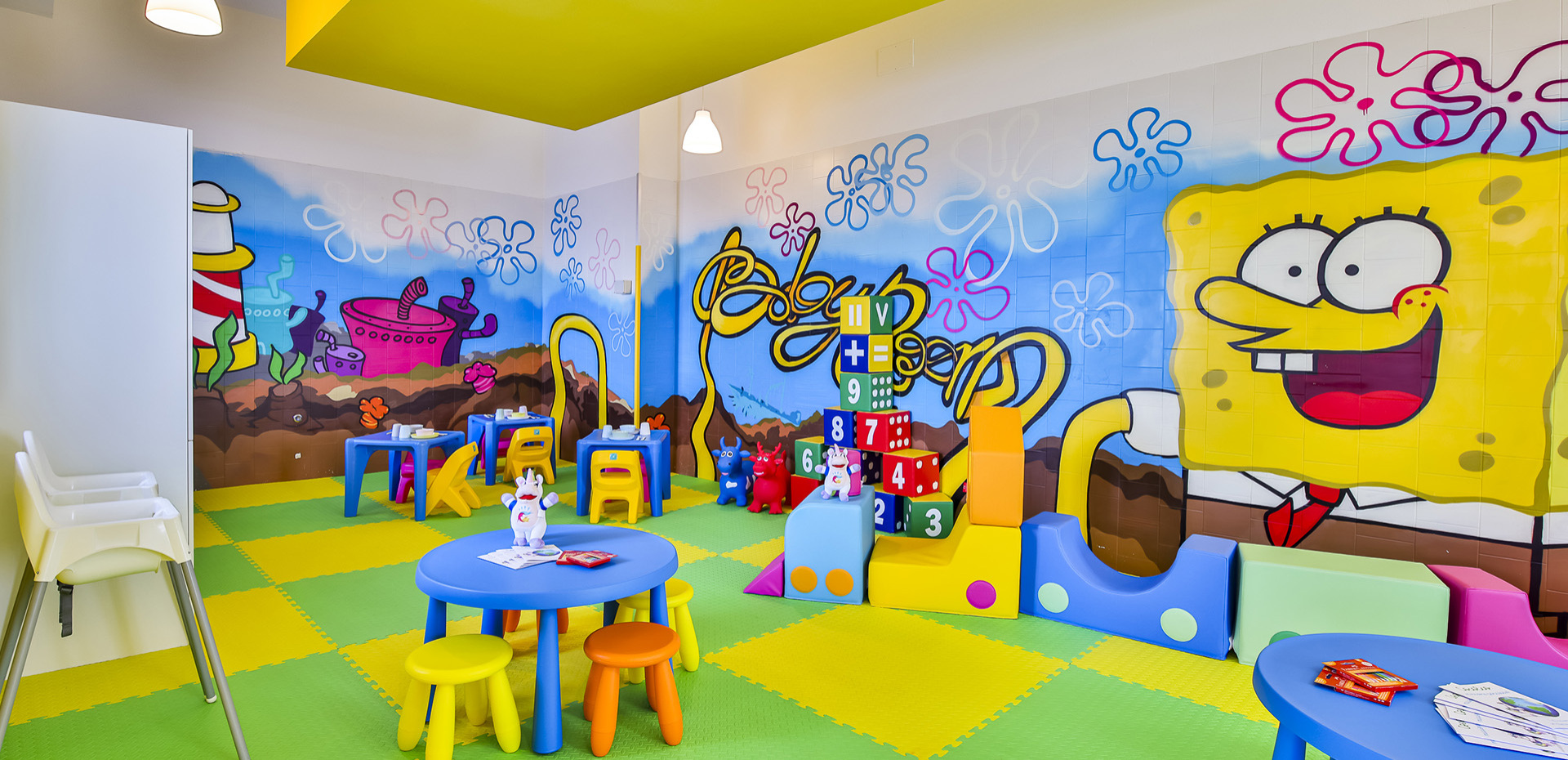 Bambina interagisce con schermo colorato, gioco educativo con animali e sfondo marino.