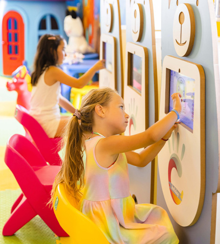 Bambina e donna giocano insieme su un tappeto colorato con giocattoli educativi.