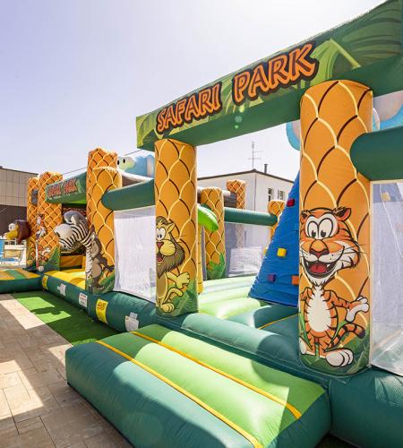 Buntes Safari Park Hüpfburg in der Nähe eines Pools, spielerische und spaßige Atmosphäre.