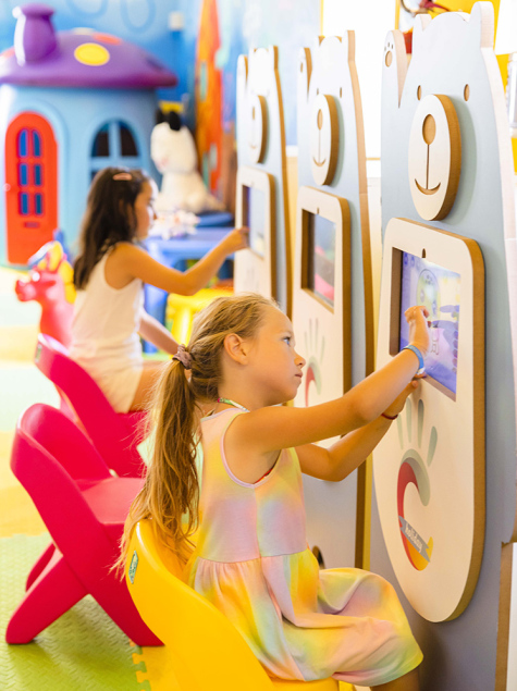 Bambina e donna giocano insieme su un tappeto colorato con giocattoli educativi.