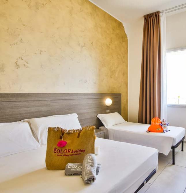 Helles Zimmer mit weißen Betten, Kinderbett, entspannendem Ausblick, ideal für Familien.